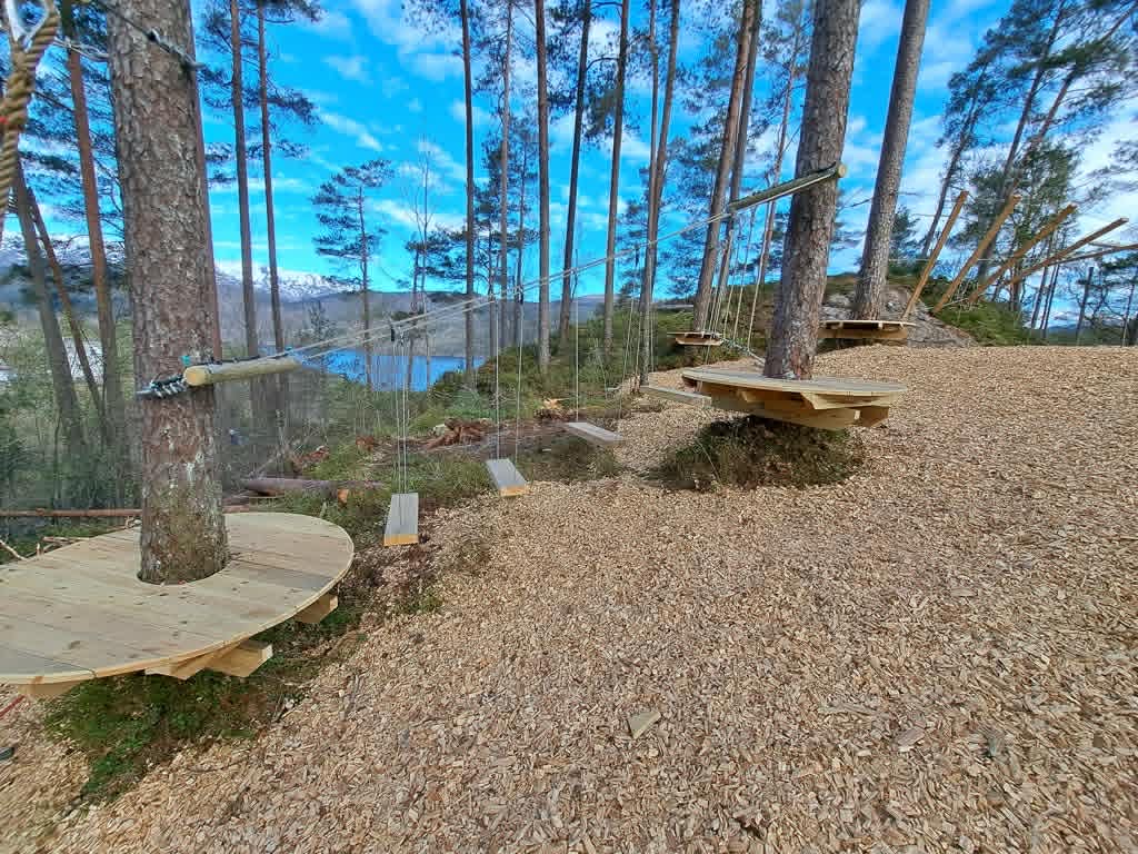 Klatrepark med treplattformer og zipline mot fjorden
